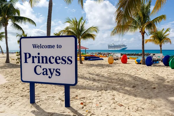 Welcome to Princess Cays sign on a palm-lined white-sand beach in The Bahamas