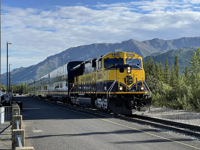 Alaska Railroad passenger train at the Denali National Park depot under a bright blue sky