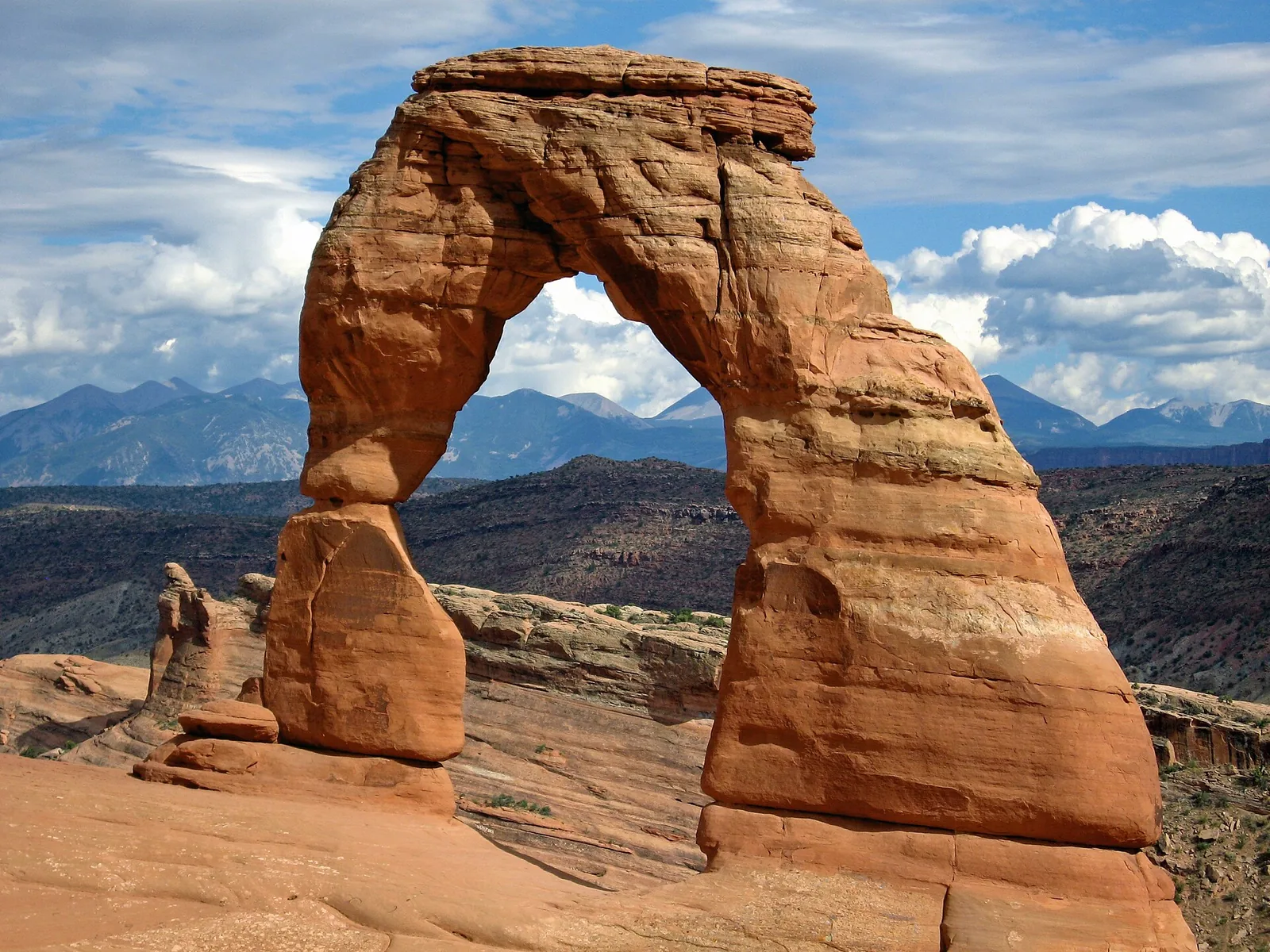 Delicate Arch glowing red-orange against snowcapped mountains in Arches National Park, Utah