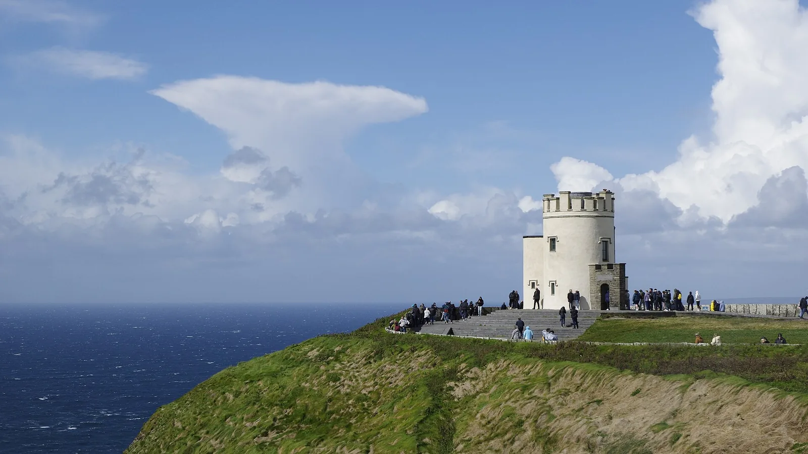 Green clifftop and O’Brien’s Tower above the blue Atlantic at the Cliffs of Moher, Ireland