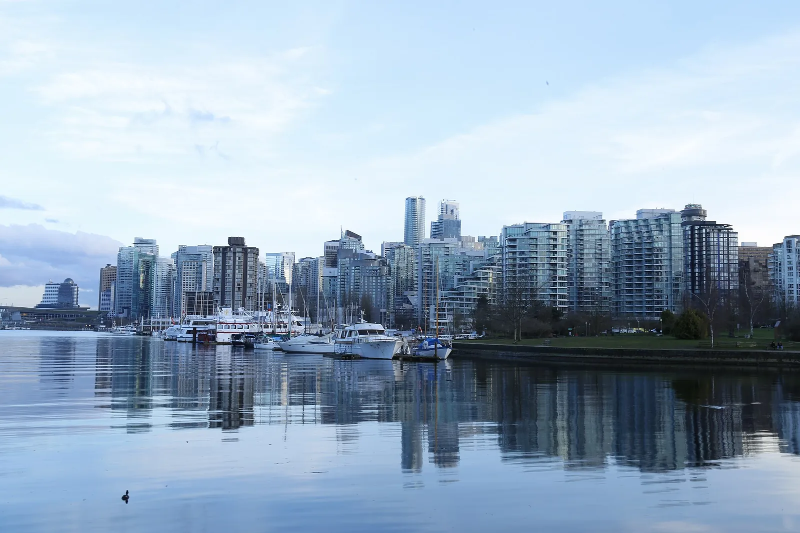 Vancouver skyline and boats on calm blue water seen from Stanley Park